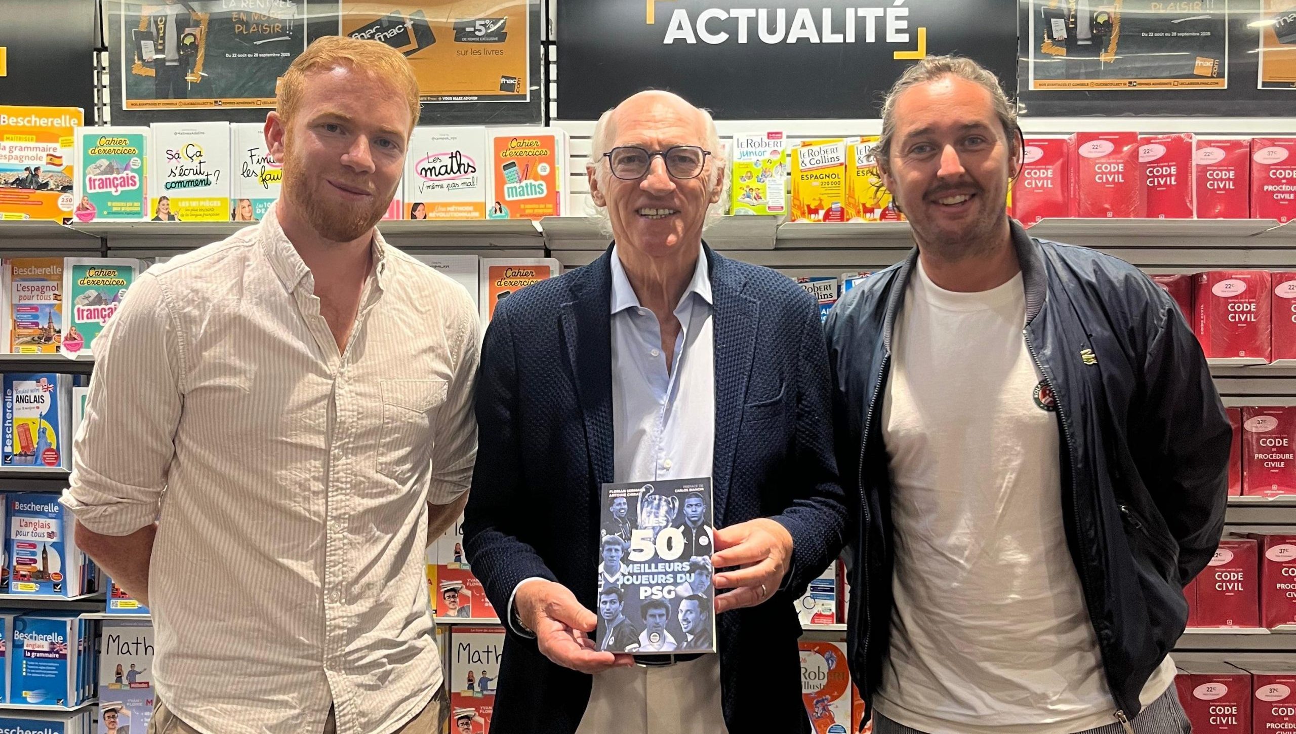 Florian Sermaise (à gauche) et Antoine Chirat (à droite) posant avec Carlos Bianchi et l'ouvrage Les 50 meilleurs joueurs du PSG.