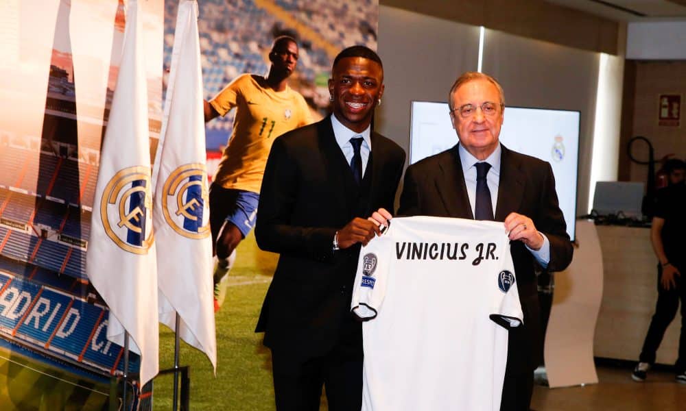 Vinicius Jr posant avec Florentino Pérez et un maillot du Real Madrid, en 2018.