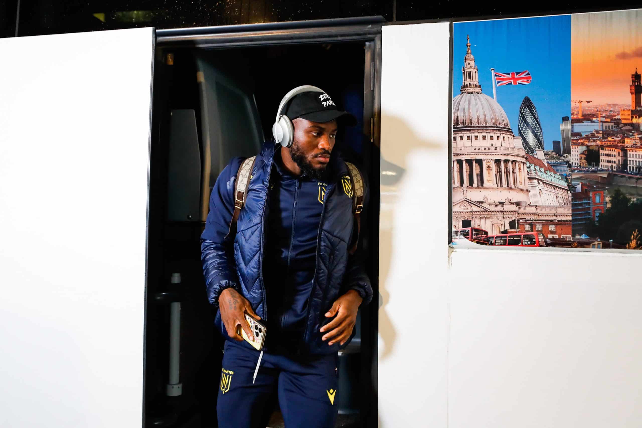 Ignatius Ganago, descendant du bus, avec le survêtement du FC Nantes et un casque audio sur les oreilles.