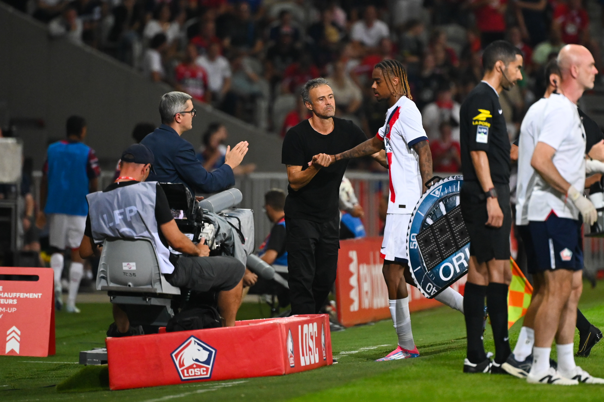 Luis Enrique saluant Bradley Barcola pendant un match du PSG.