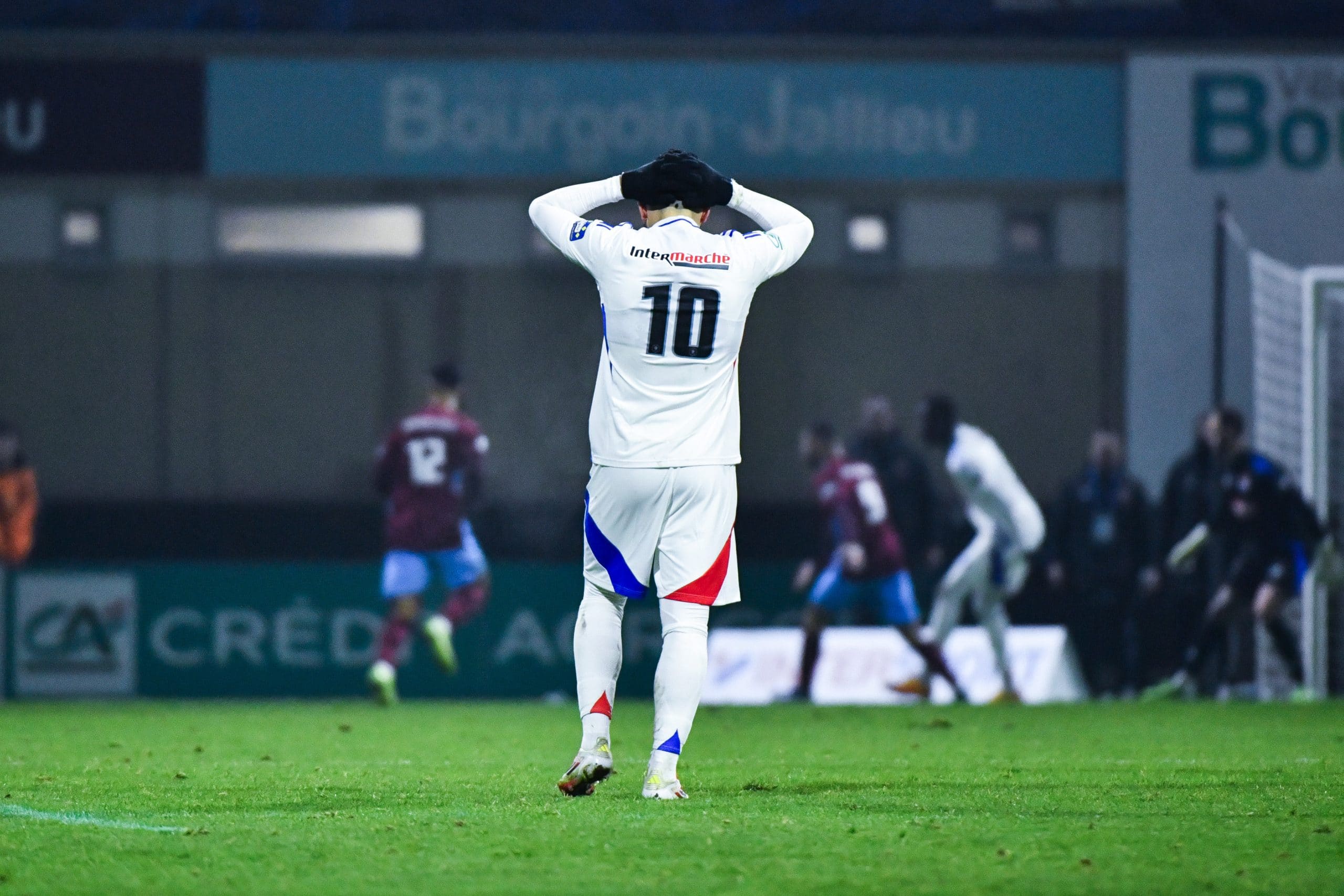 Rayan Cherki se tient la tête à deux mains après l'élimination de l'OL sur la pelouse de Bourgoin-Jallieu.