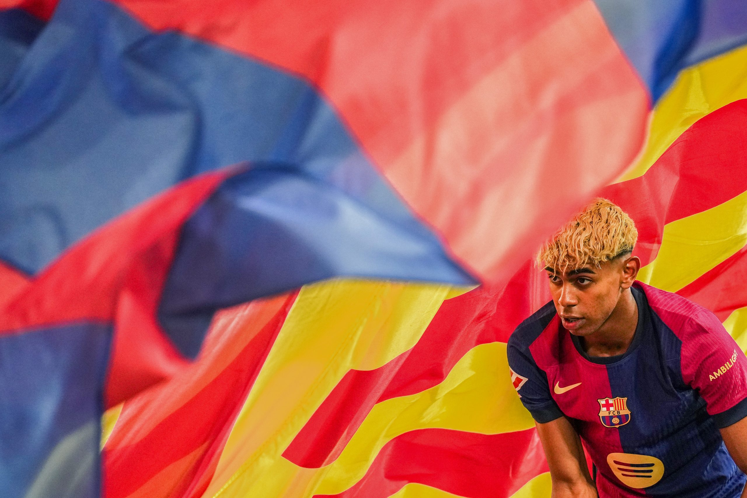 Lamine Yamal sous un drapeau du FC Barcelone.