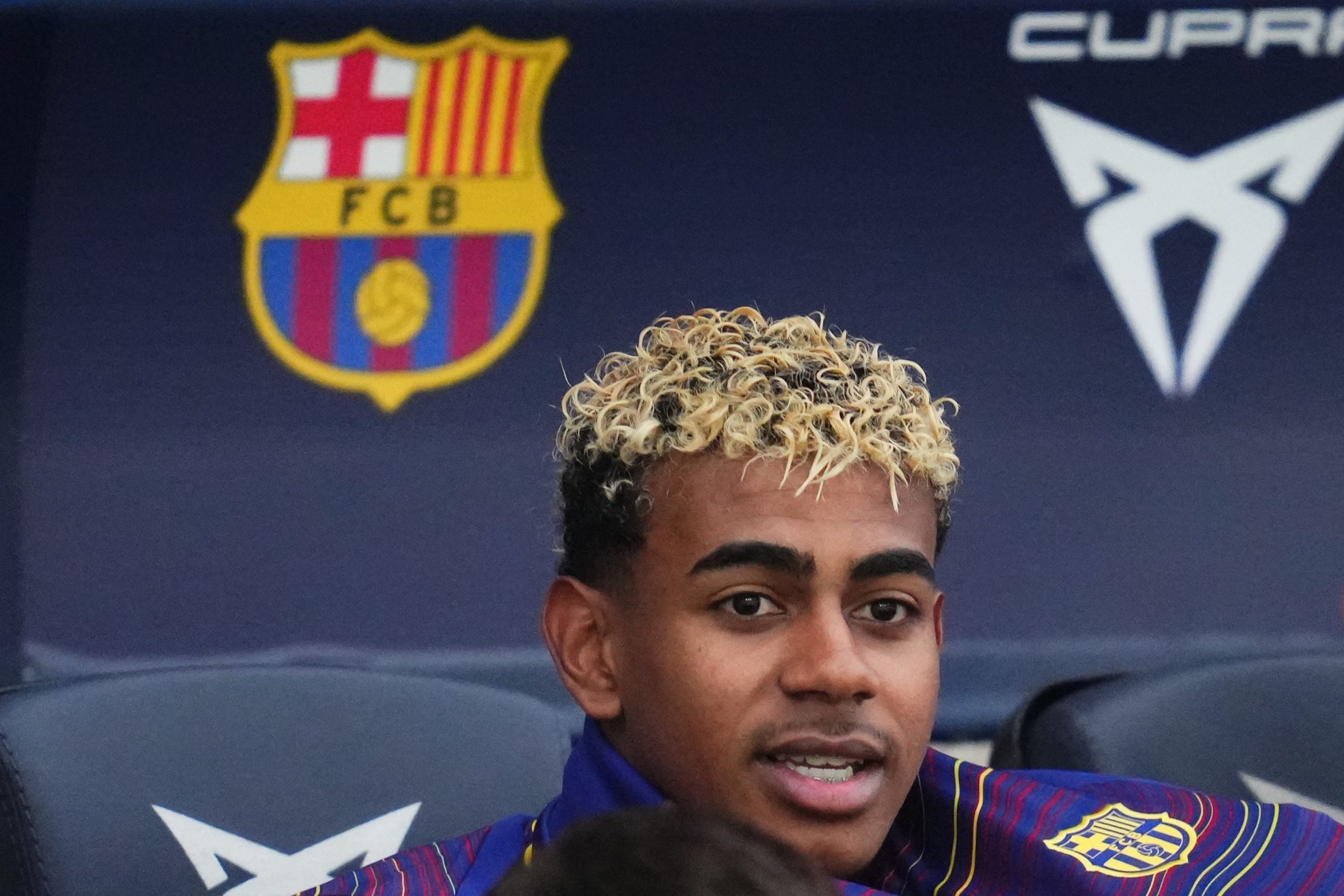 Lamine Yamal avec l'écusson du FC Barcelone derrière lui.