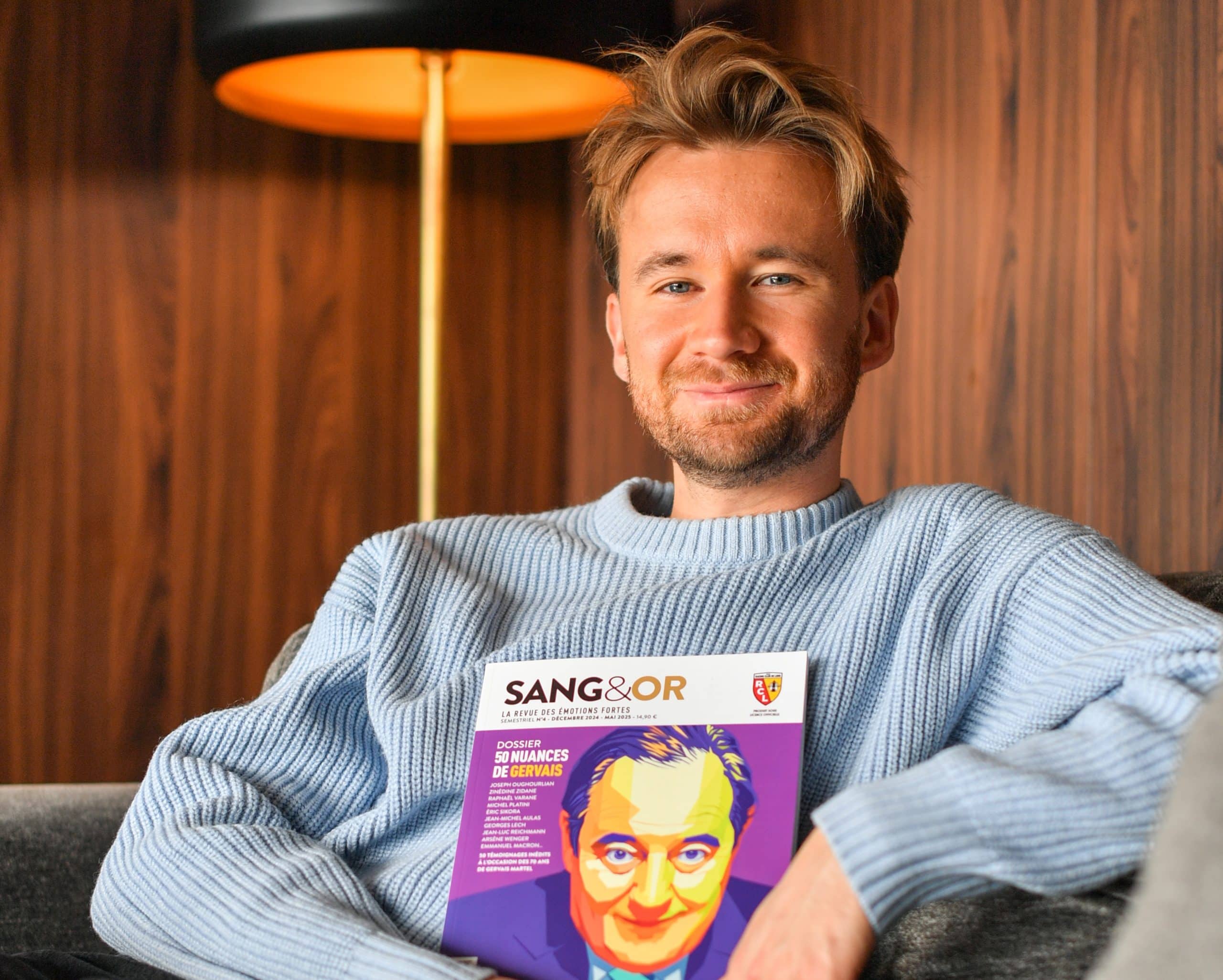 Bastien Kossek, supporter du RC Lens, qui pose avec le dernier numéro du magazine "Sang et Or".