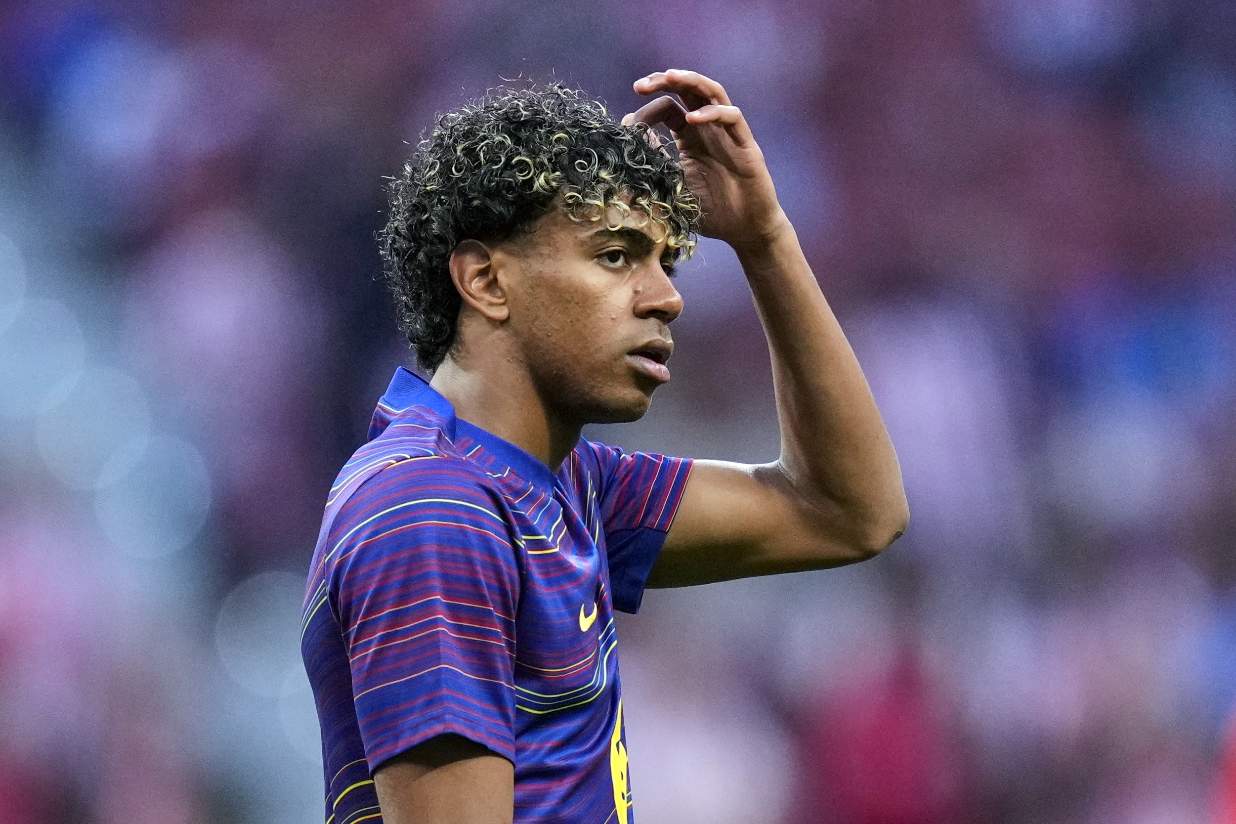 Lamine Yamal se grattant la tête lors d'un échauffement du FC Barcelone.